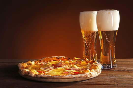 Artisan pizza slice with craft beer at QuartHaus